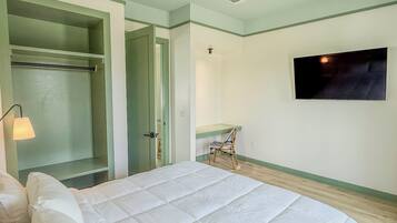 Un dormitorio con cama, televisor, silla y armario.