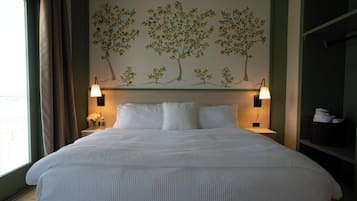 A hotel room with a large bed, two bedside lamps, a wall-mounted shelf, and a window with curtains.