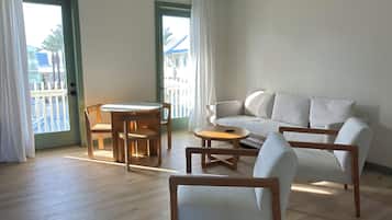 A spacious living room with a sofa, chairs, a dining table, and a hanging light fixture.