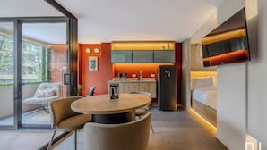 Une chambre d’hôtel moderne dotée d’un coin repas, d’une kitchenette et d’un lit.