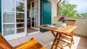 A balcony with a wooden table, chairs, and a potted plant. - Villa with pool and air conditioning (Orbanići)