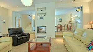 A spacious living room with a fireplace, a dining area, and a staircase leading to another level. - Villa with pool and air conditioning (Orbanići)