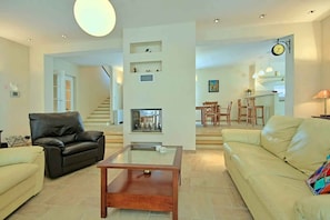 Una sala de estar amplia con chimenea, un comedor y una escalera que sube a otro nivel.