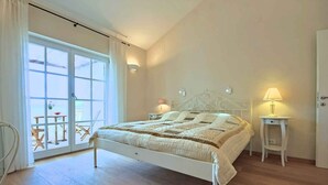 A bedroom with a large bed, a sliding glass door to a balcony, and a small table with a lamp. - Villa with pool and air conditioning (Orbanići)