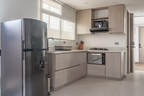 A modern kitchen with a stainless steel refrigerator, wooden cabinets, a microwave, and a built-in oven. - NOK Stylish Studio w Balcony in Laureles Medellin (Medellín)