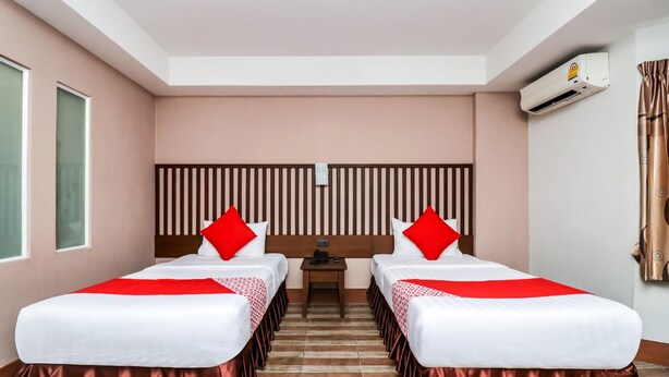 A hotel room with two beds, a headboard, a nightstand, and an air conditioning unit. - Ja Siam City (Pattaya)