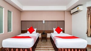 A hotel room with two beds, a headboard, a nightstand, and an air conditioning unit. - Ja Siam City (Pattaya)