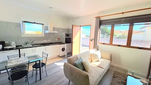 A compact living space with a kitchenette, a dining area, and a sofa. - Studio Apartment (Santana)