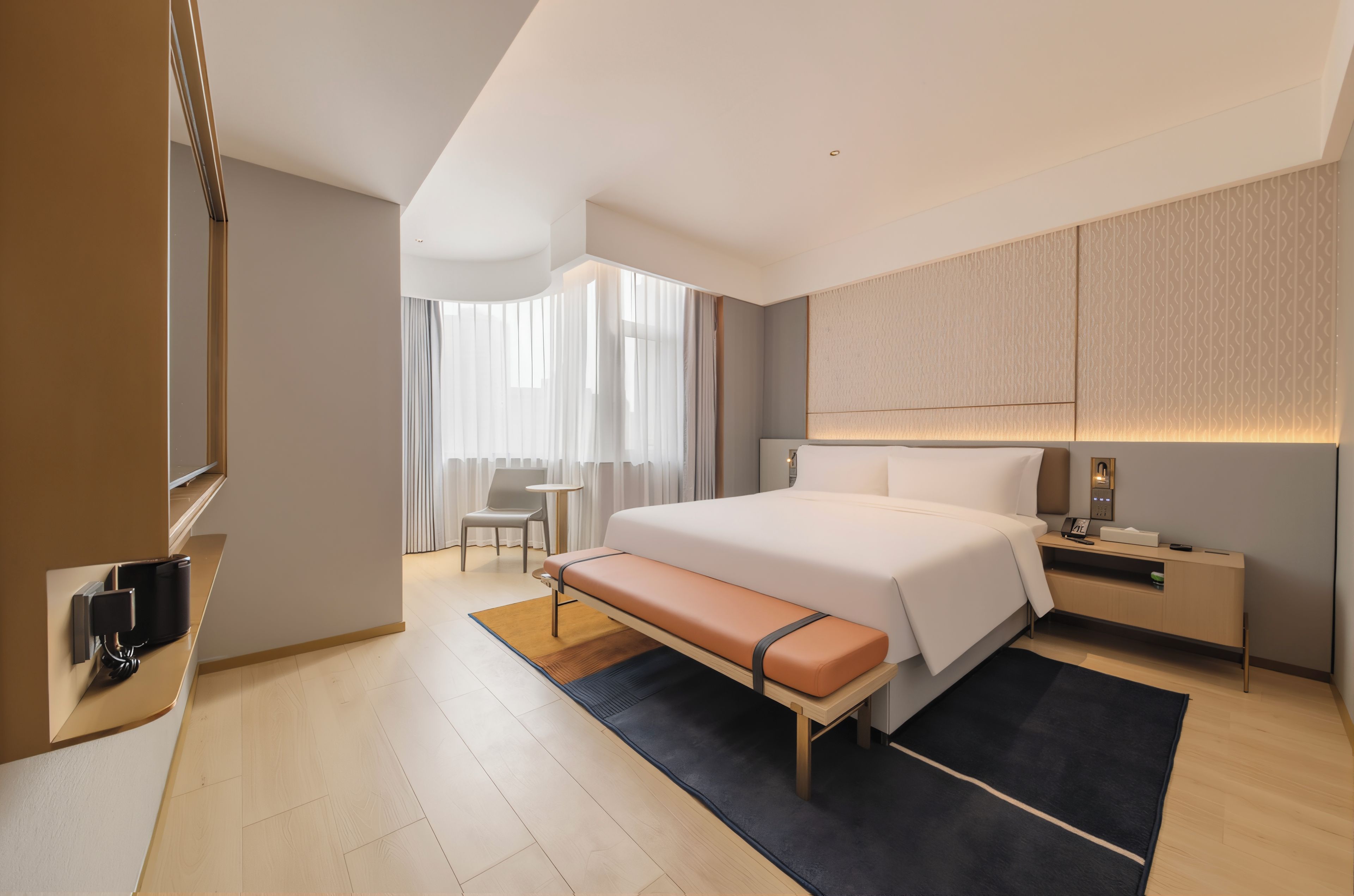 Una habitación de hotel moderna con una cama grande, mesitas de noche, un escritorio y una silla.