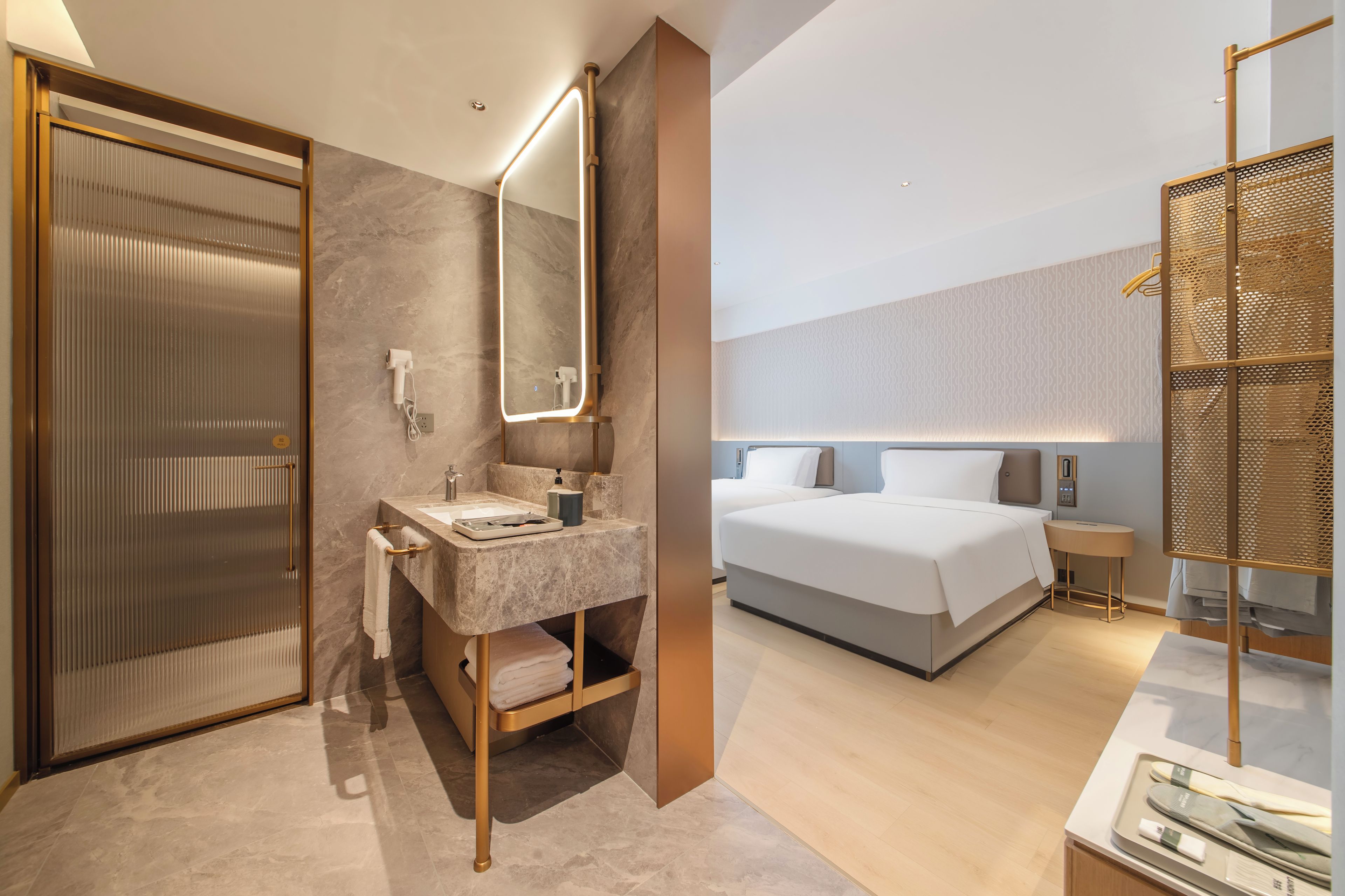 A modern hotel room with a bathroom, a bed, and a walk-in closet.