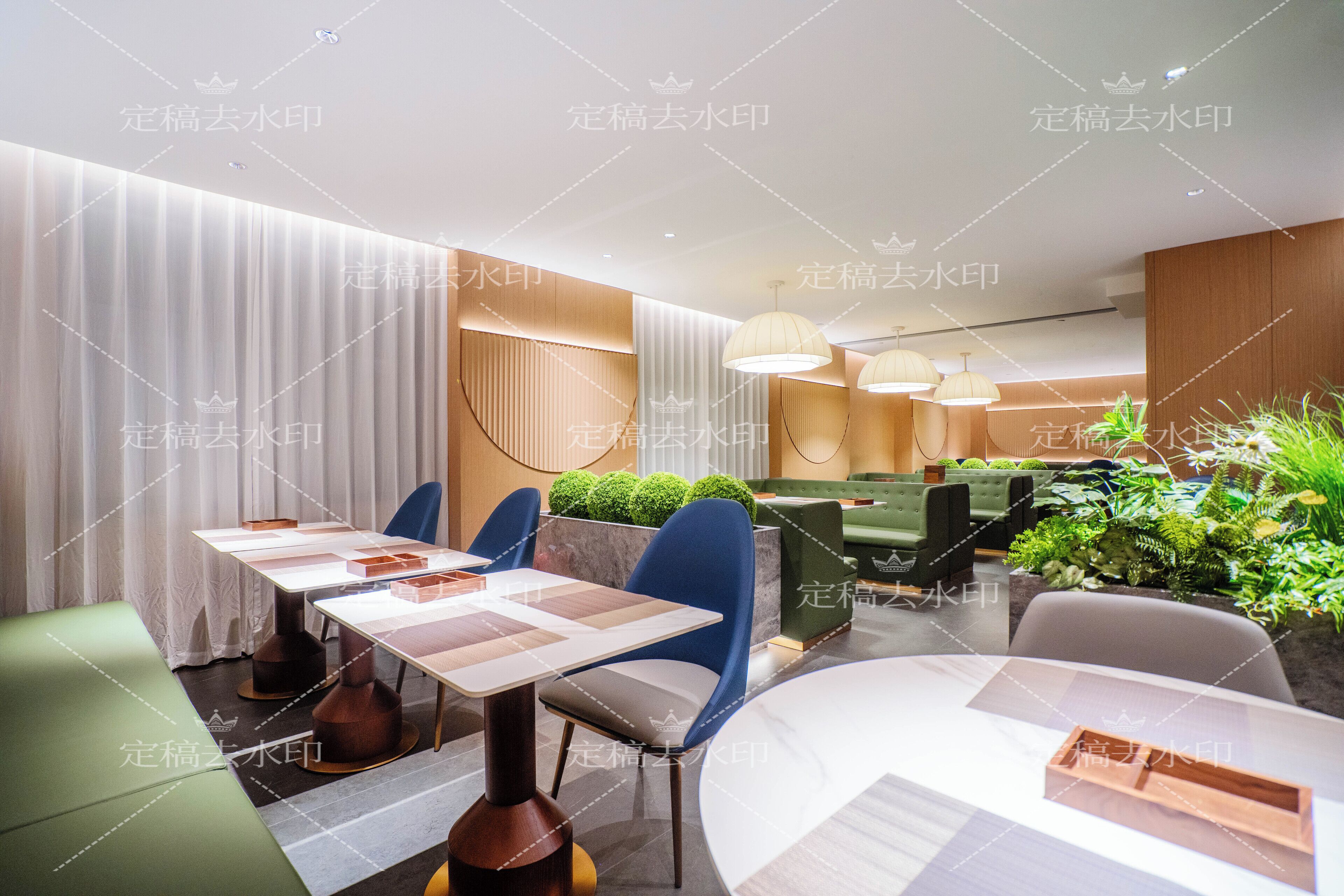 En moderne restaurant med spiseområde, borde, stole, en grøn sofa og en lille indendørs have.