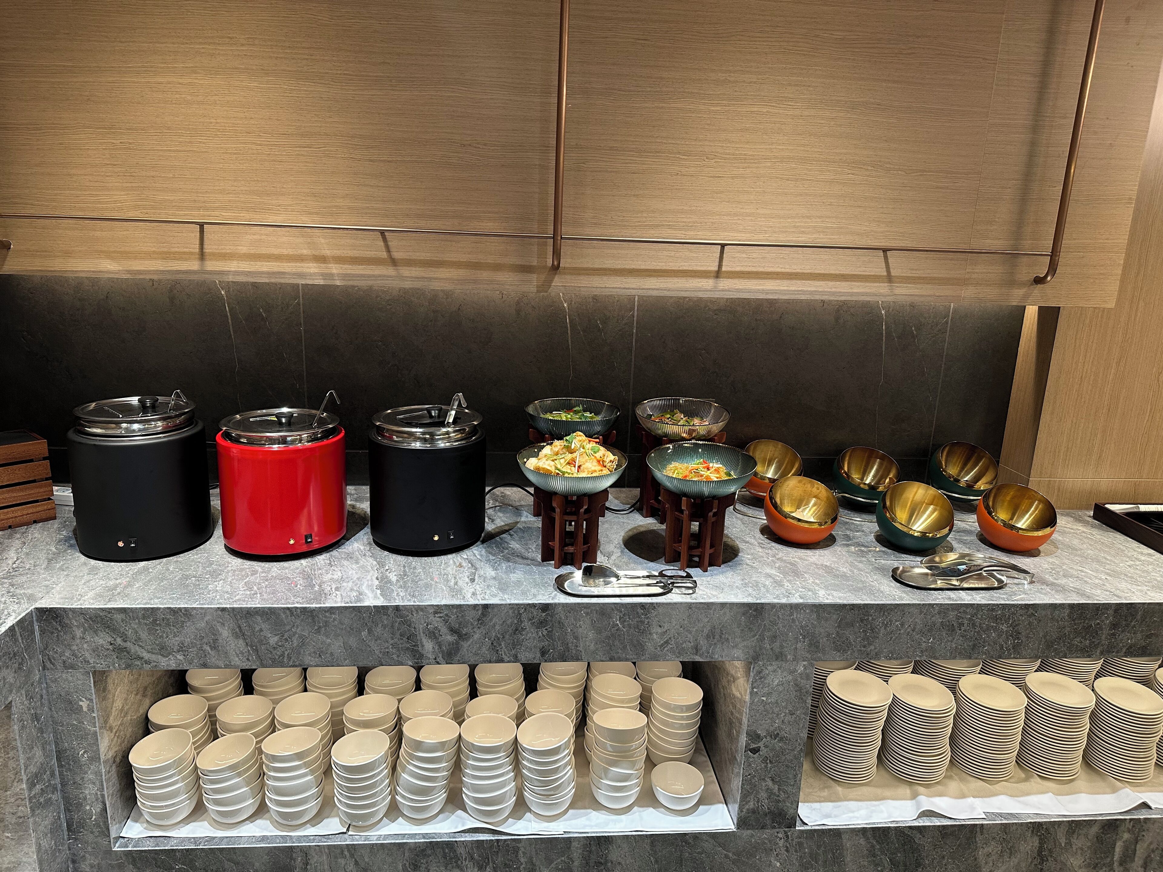A buffet setup with various food containers and bowls.