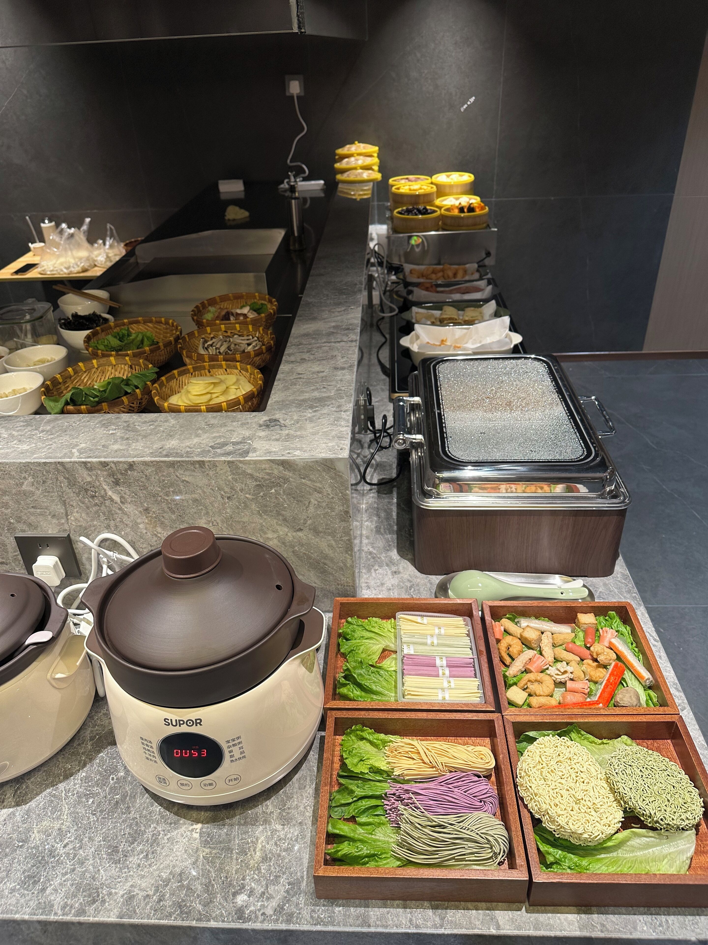 A buffet setup with various food items and cooking equipment.