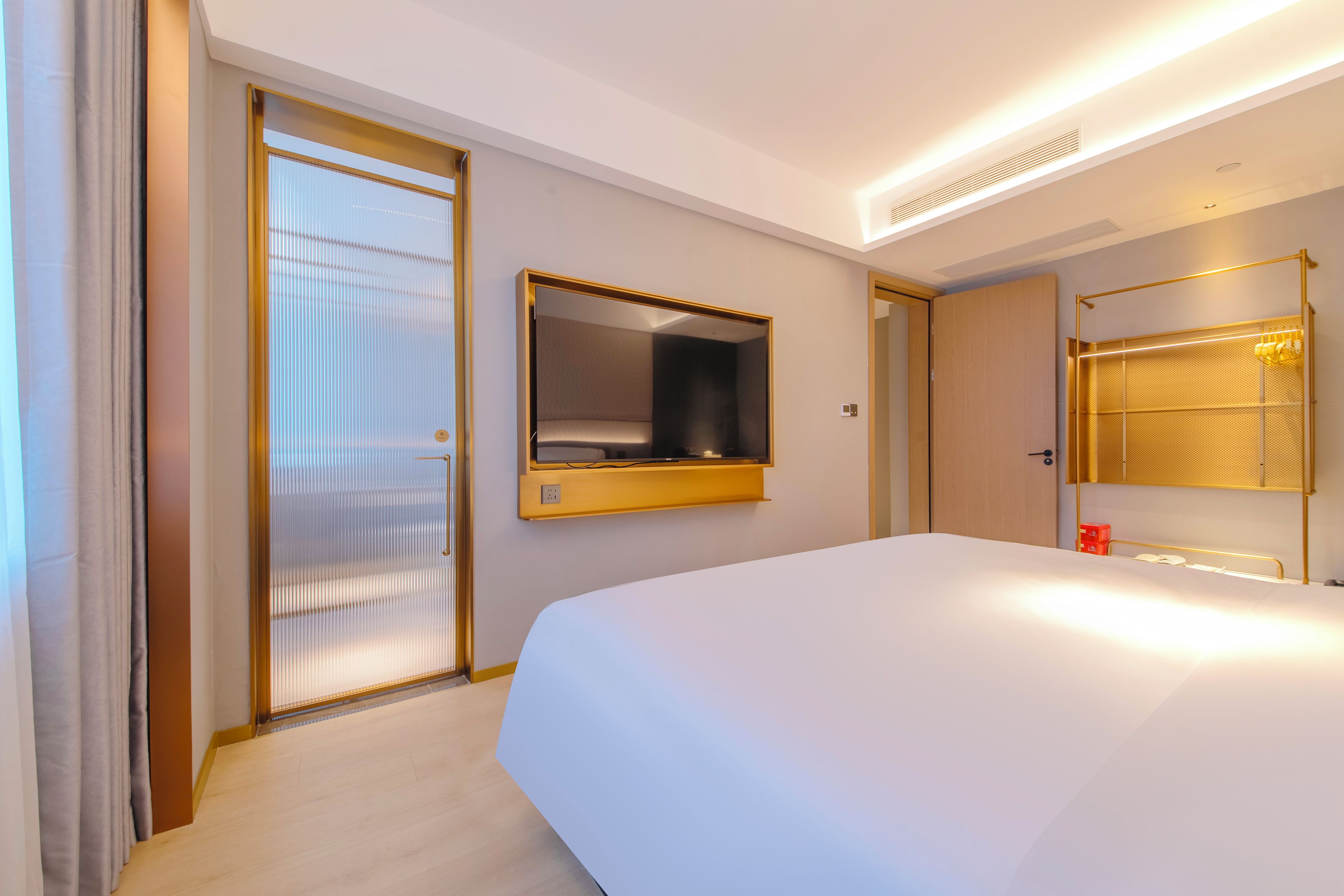 A hotel room with a large bed, a mirror, a wardrobe, and a sliding door.
