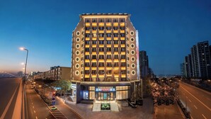 Um hotel moderno com entrada imponente, vários andares e fachada bem iluminada.