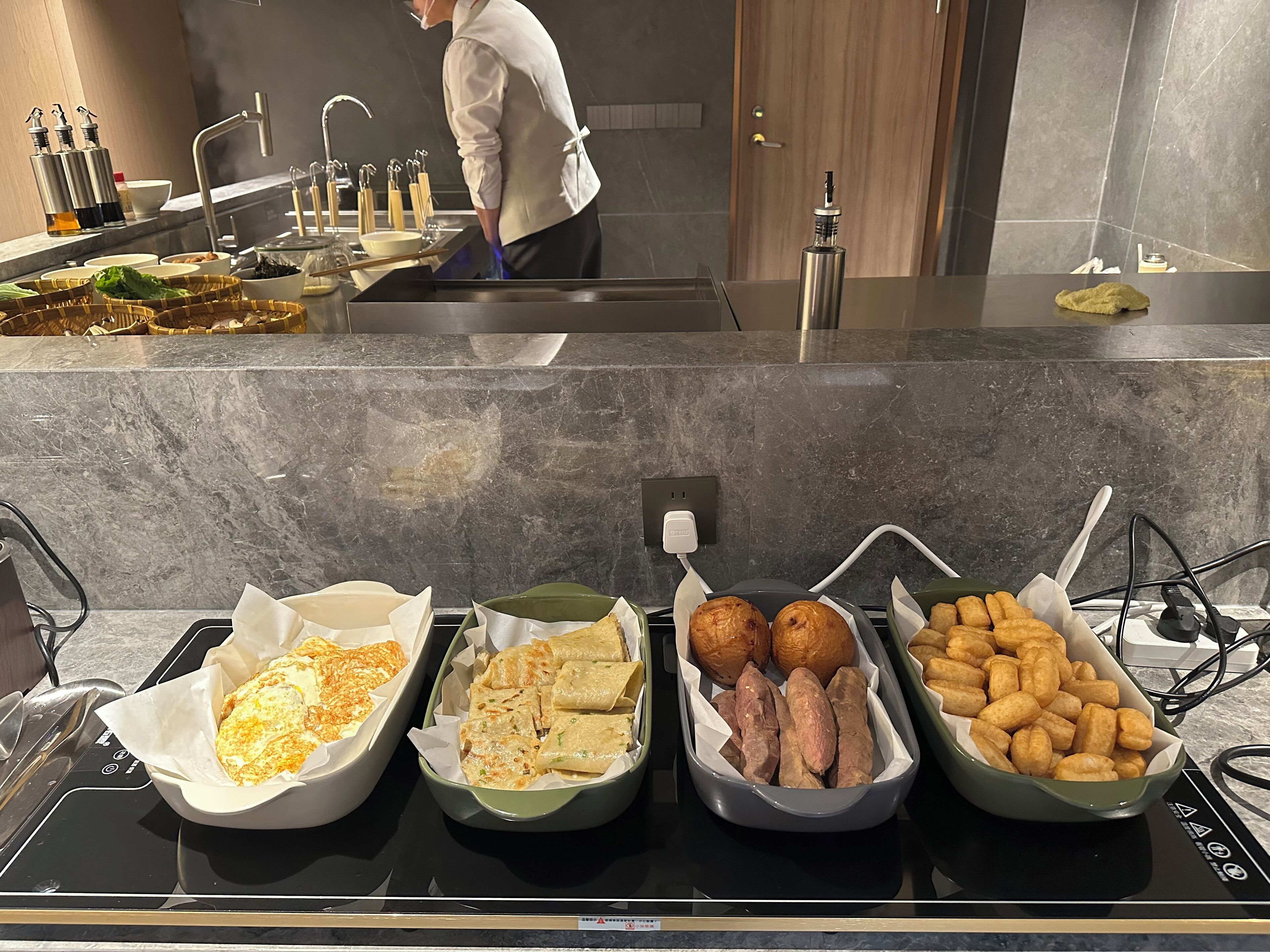 Een buffet met diverse gerechten, waaronder frites, zoete aardappelen en andere bereide maaltijden.