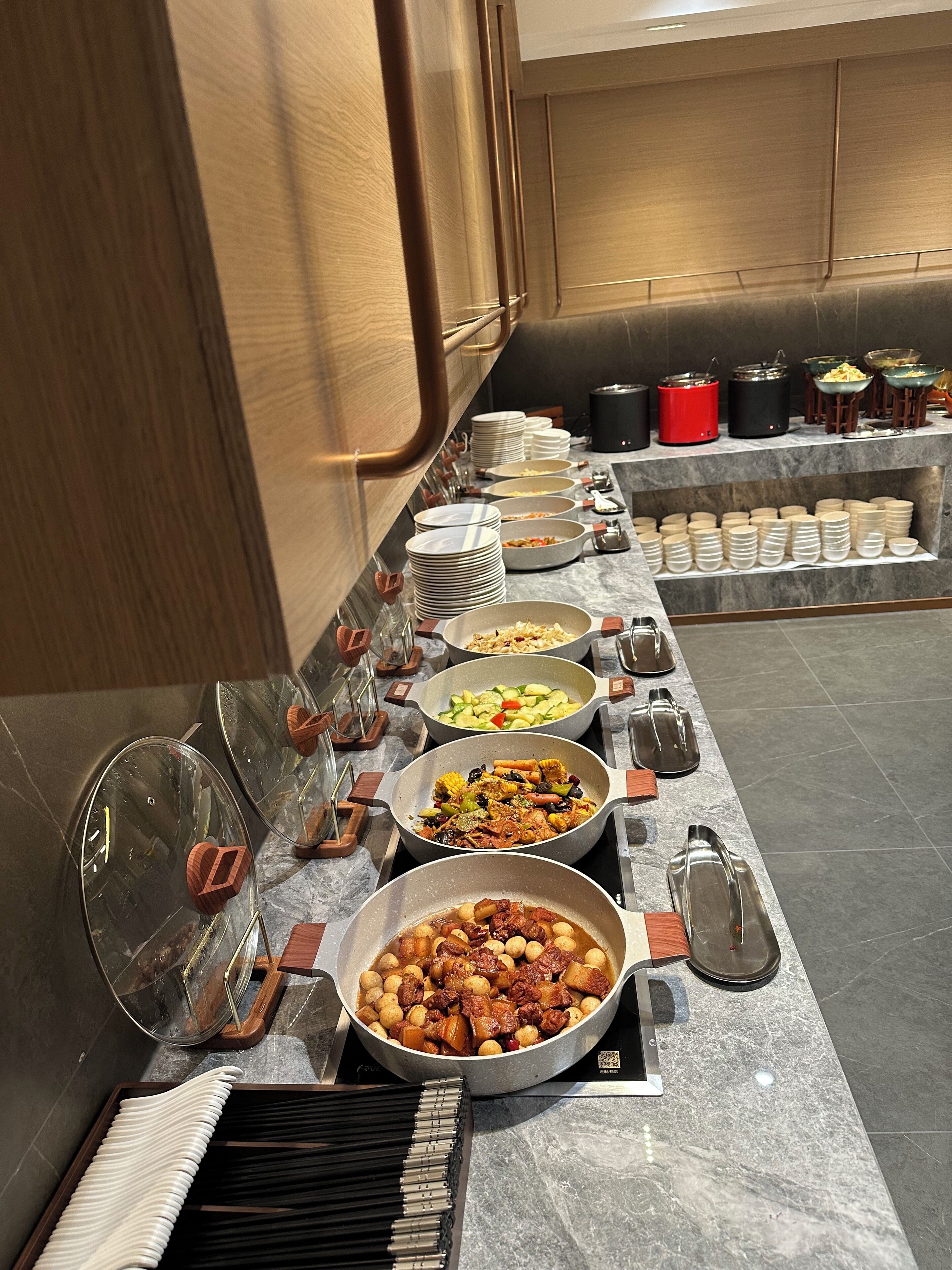 A buffet setup with various dishes and utensils.
