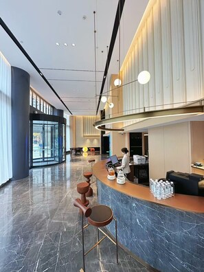 A modern hotel lobby with a reception desk, seating area, and large windows. - Echarm Plus Hotel (Taiyuan)