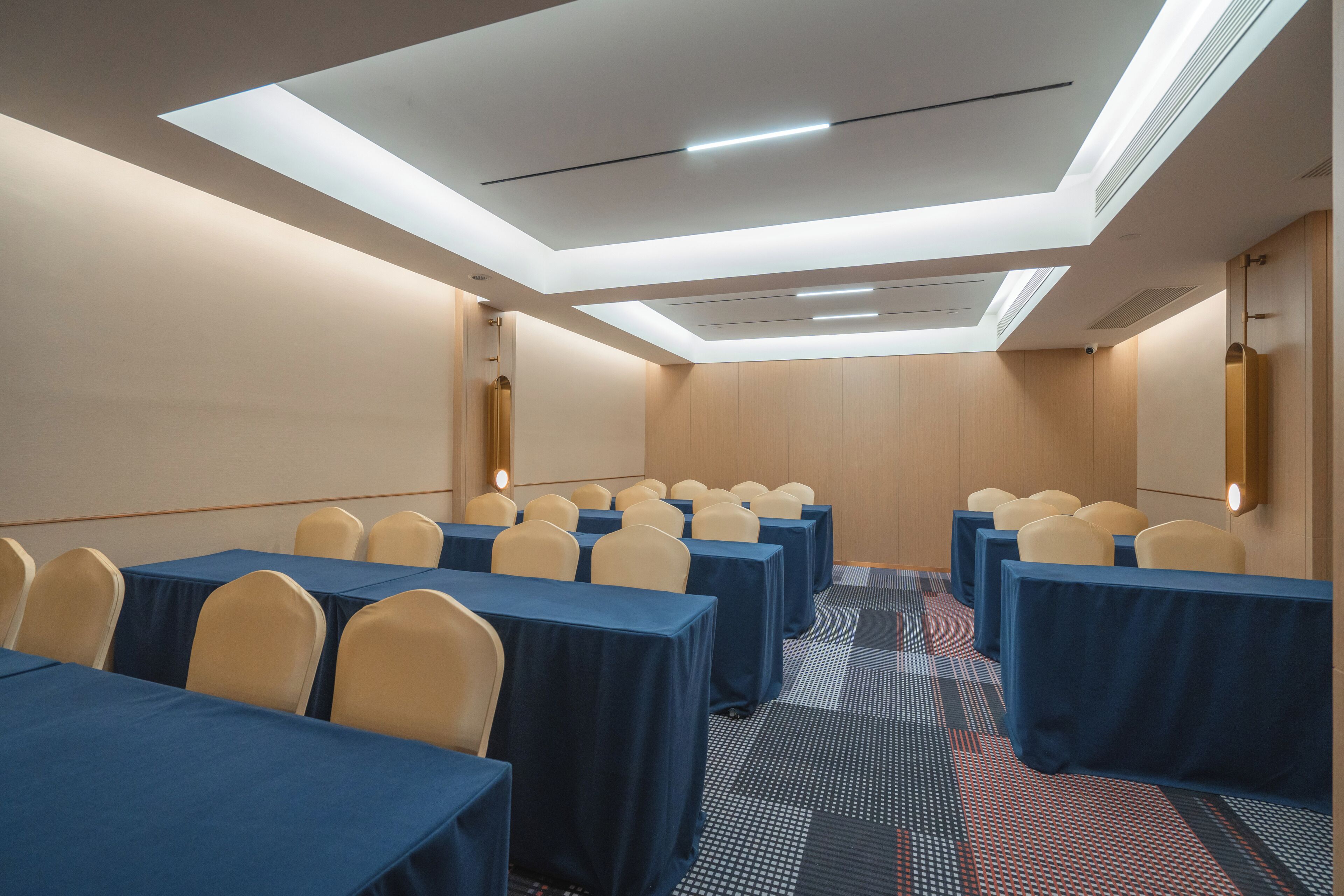 A conference room with tables and chairs, a patterned carpet, and a skylight ceiling.