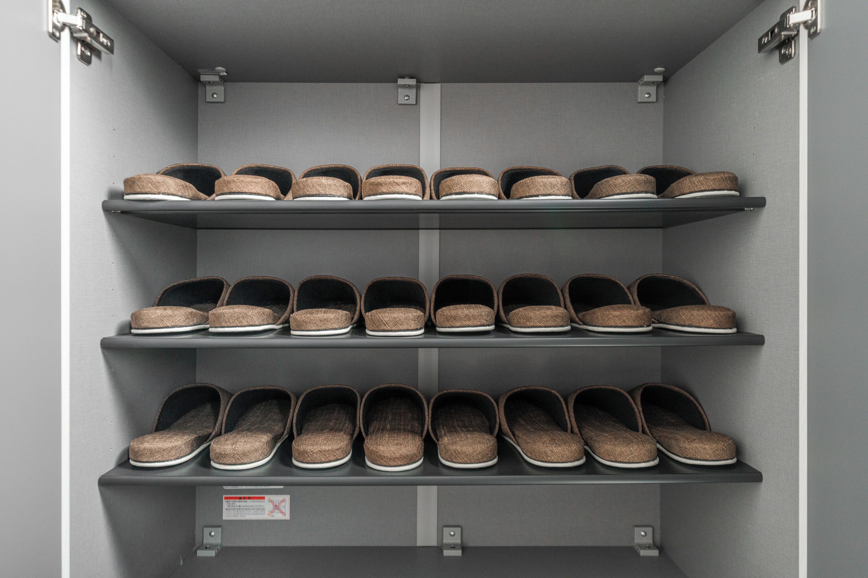 A shoe storage unit with multiple shelves holding various pairs of shoes.