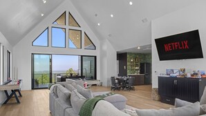 A spacious living area with a large window, a flat-screen TV, and a pool table. - Eagle`s Vista · Heated Pool, Stunning Views, Hot Tub & Game Room - Sleeps 30! (Broken Bow)