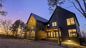 A two-story house with a prominent gable roof, large windows, and a covered porch area. - Eagle`s Vista · Heated Pool, Stunning Views, Hot Tub & Game Room - Sleeps 30! (Broken Bow)