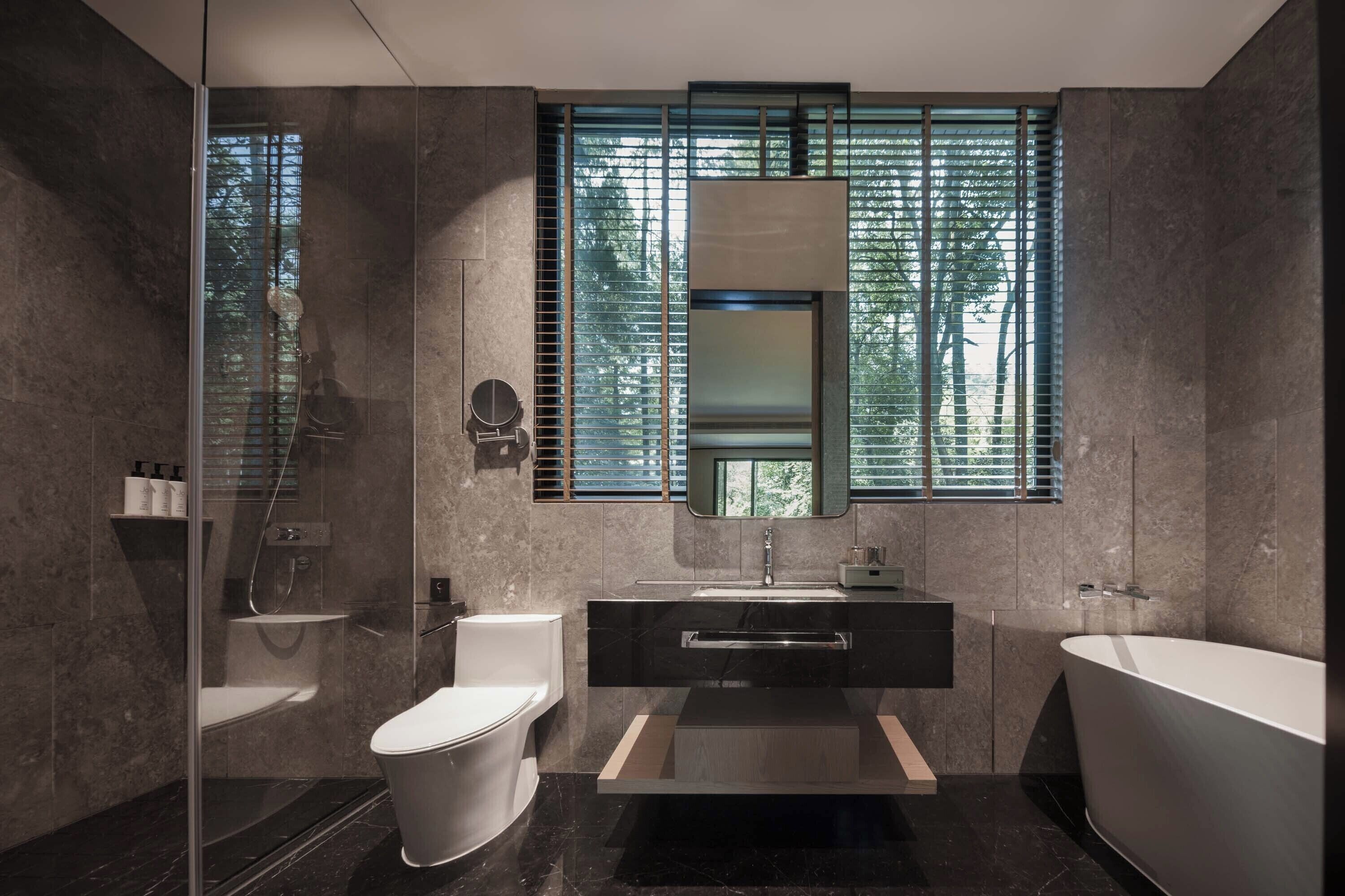 A modern bathroom with a glass-enclosed shower, a toilet, a sink, and a bathtub.