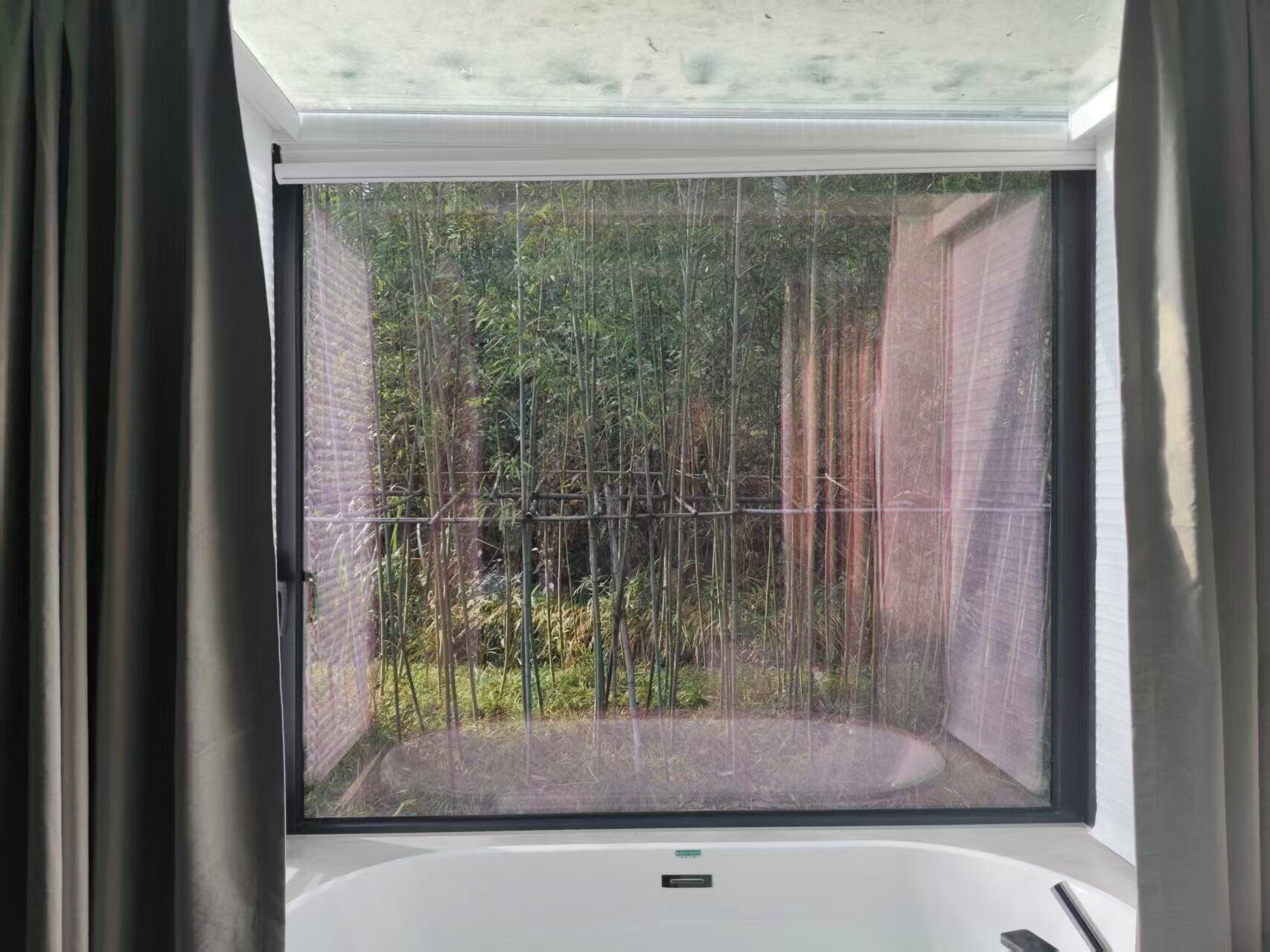 A bathroom with a large window, a bathtub, and a shower area.