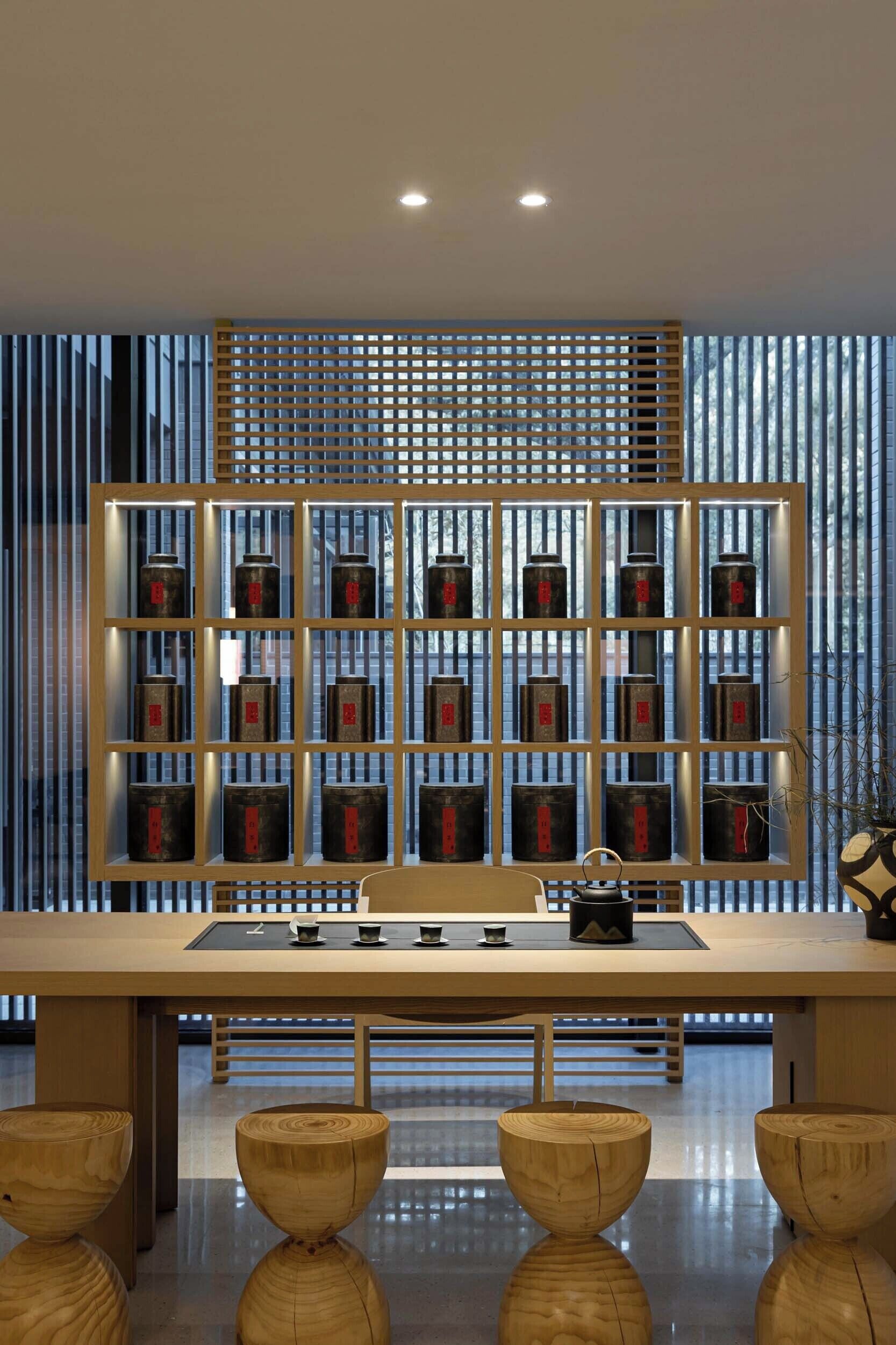 A modern interior with a wooden table, a decorative shelf with jars, and a vertical wooden slat wall.
