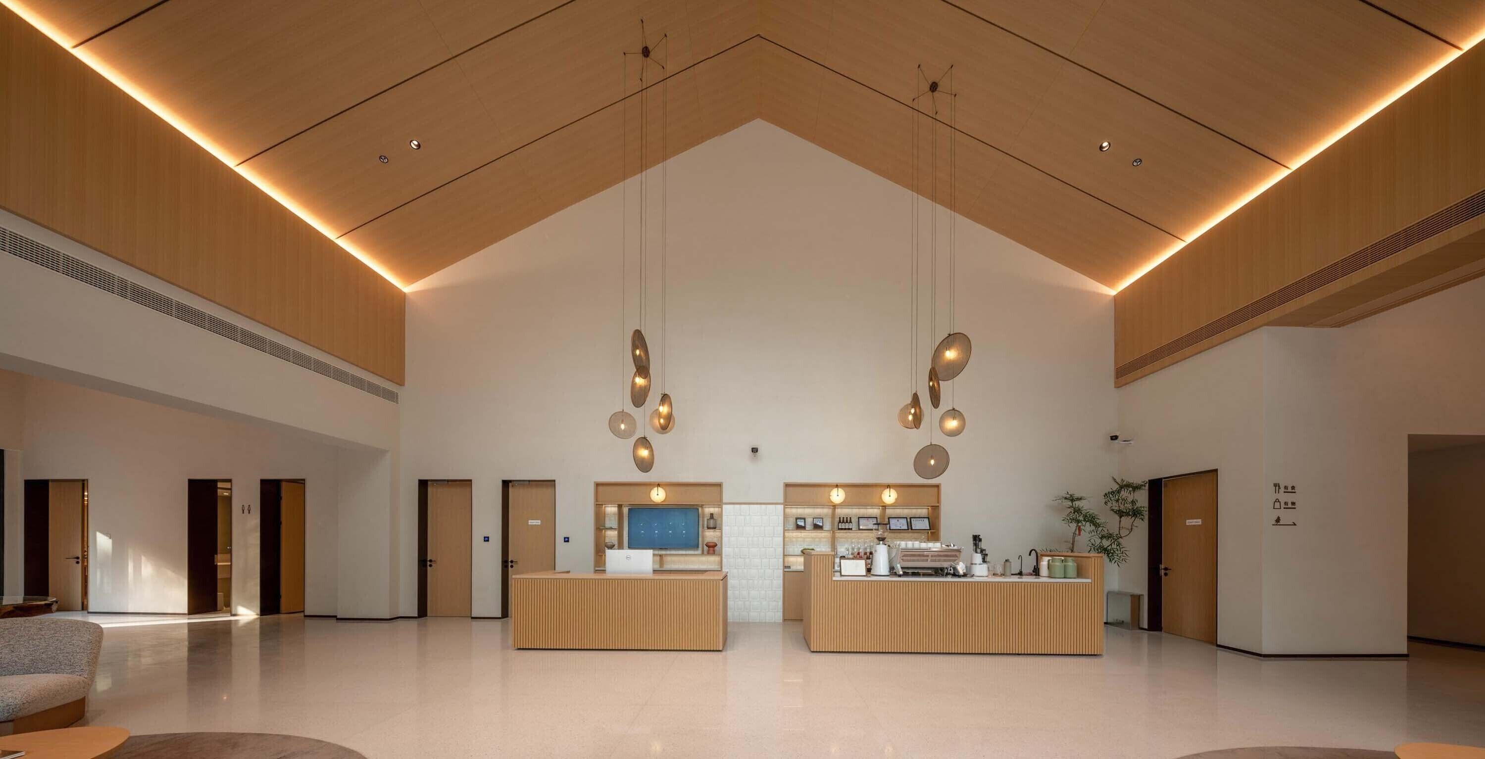 A spacious lobby with a reception desk, seating area, and a large television screen.
