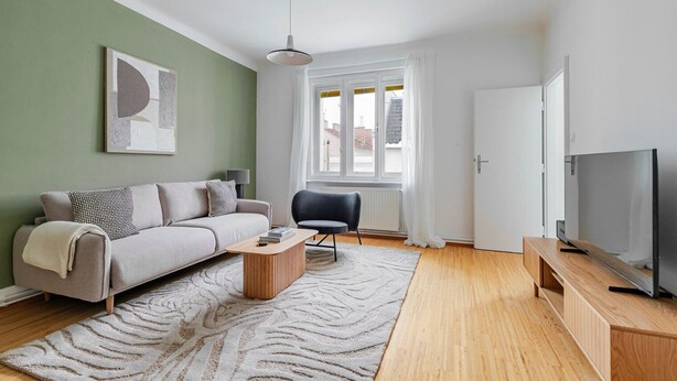 A modern living room with a sofa, armchair, coffee table, and TV stand. - Blueground | Josefstadt, view, nr Rathaus (Vienna)