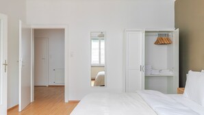 A hotel room with a large bed, a wardrobe with hanging space, and a view through an open door. - Blueground | Josefstadt, view, nr Rathaus (Vienna)