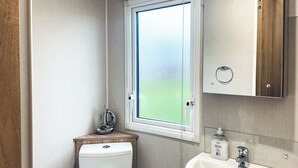 Un baño pequeño con inodoro, ventana, lavamanos y espejo.