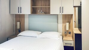 Una habitación de hotel con cama, mesita de noche, armario y espejo.