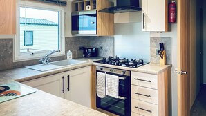 Una cocina moderna con estufa a gas, horno, microondas y una ventana con persianas.