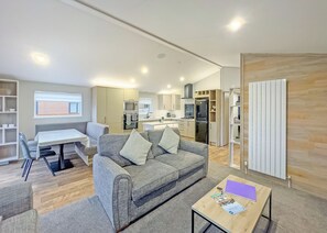 A modern living room with a sofa, a dining table, and a kitchen area in the background.