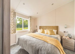 A bedroom with a bed, a nightstand, a lamp, and a window with curtains.