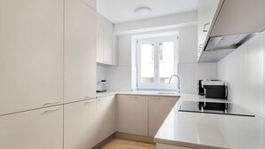 Una cucina moderna con mobili bianchi, un piano di lavoro nero e una finestra sopra il lavello.