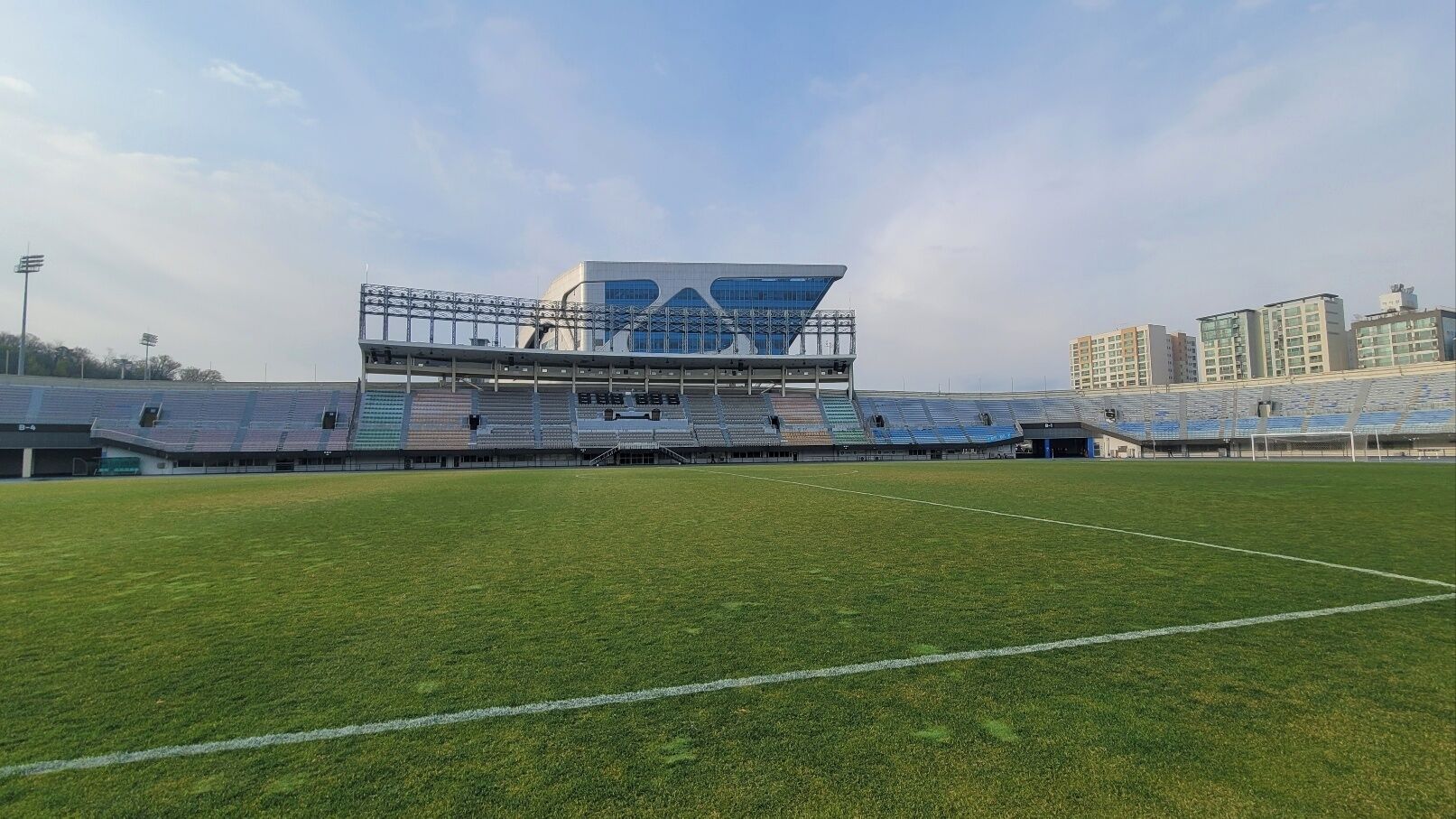 A large, modern stadium with multiple tiers of seating and a well-maintained grass field.
