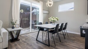 A modern dining area with a table and chairs, a vase with flowers, and a view of the outdoors. - Cozy Modern Home! (Vancouver)
