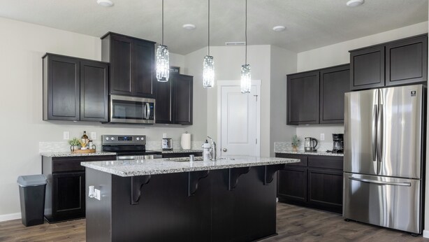 A modern kitchen with dark cabinetry, stainless steel appliances, and a central island. - Cozy Modern Home! (Vancouver)