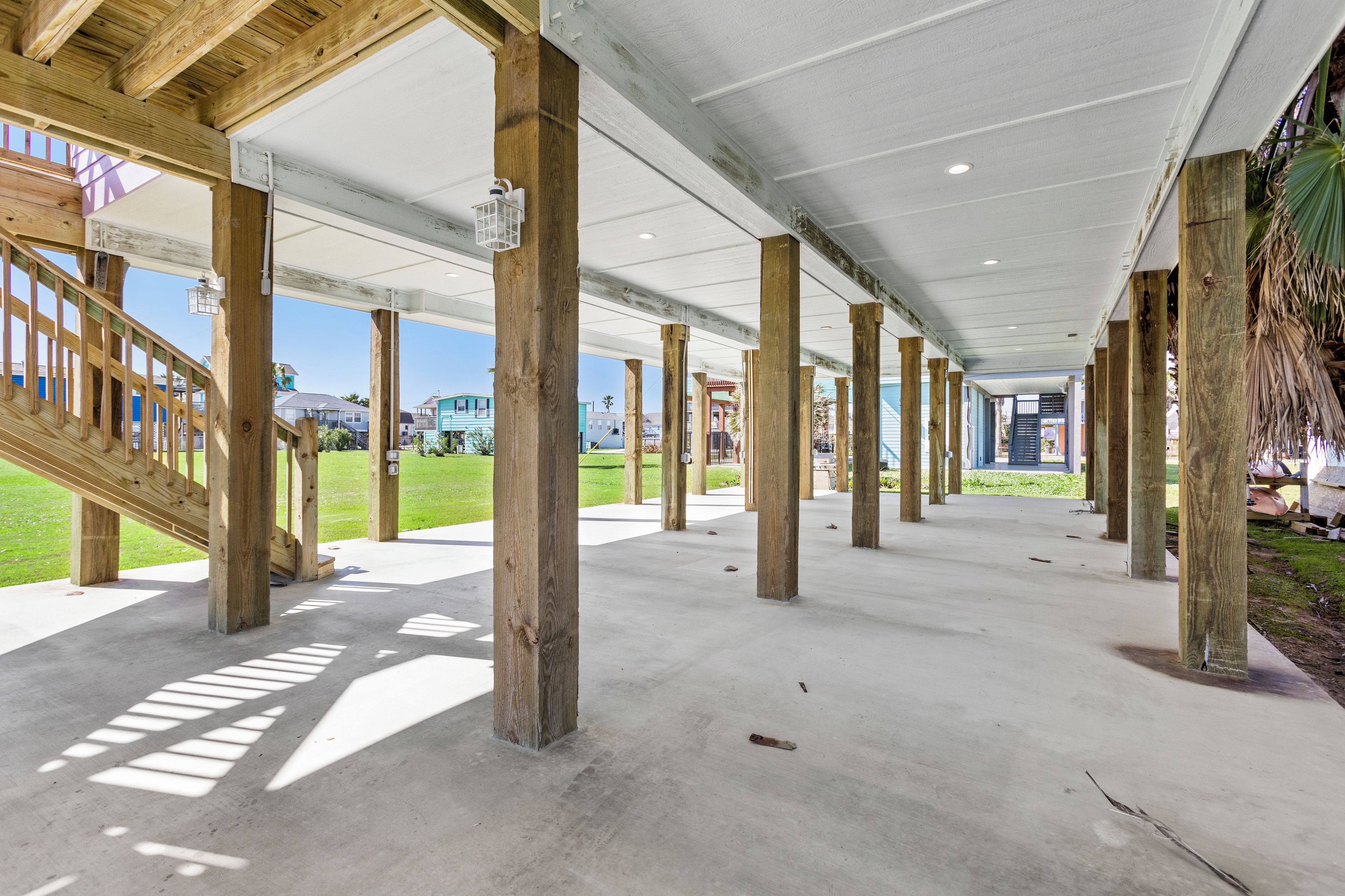 Un’area esterna coperta con pavimento in cemento e travi in legno che sorreggono il soffitto.