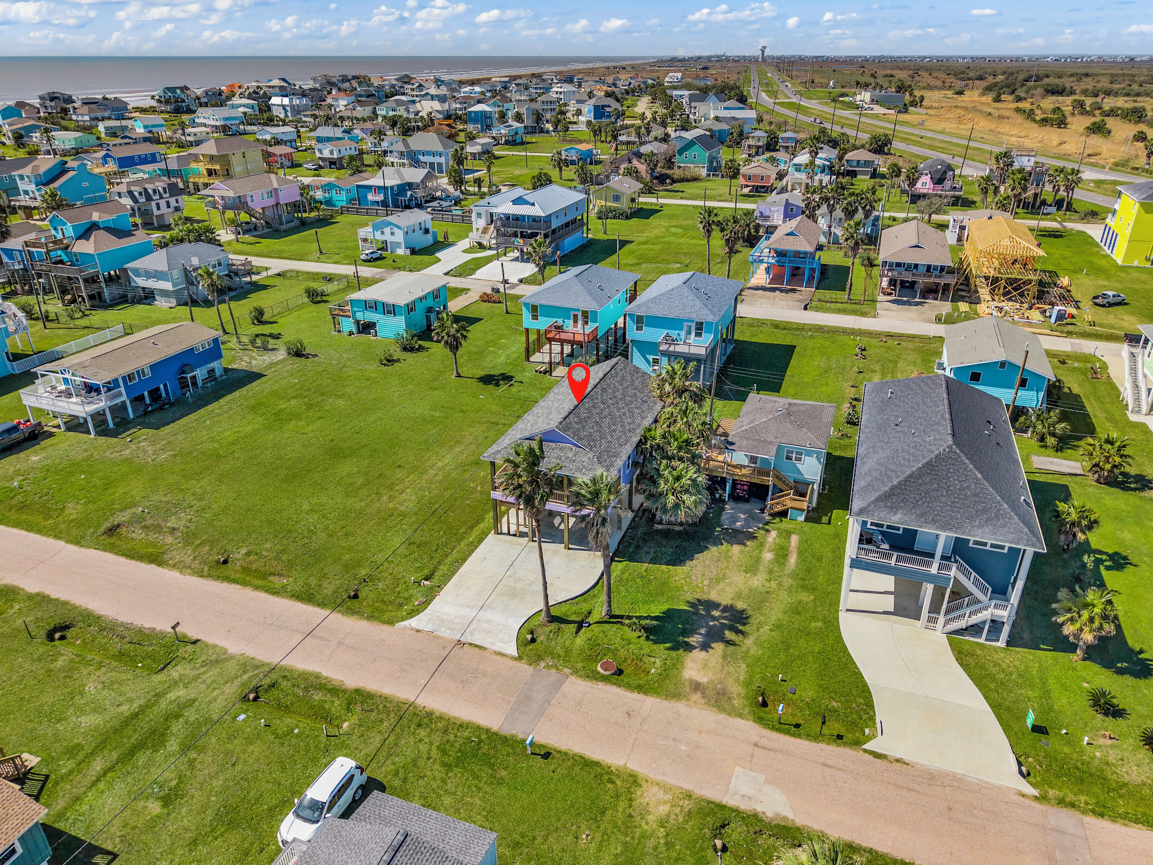 Vista aérea de una zona residencial costera con casas, carreteras y una playa al fondo.