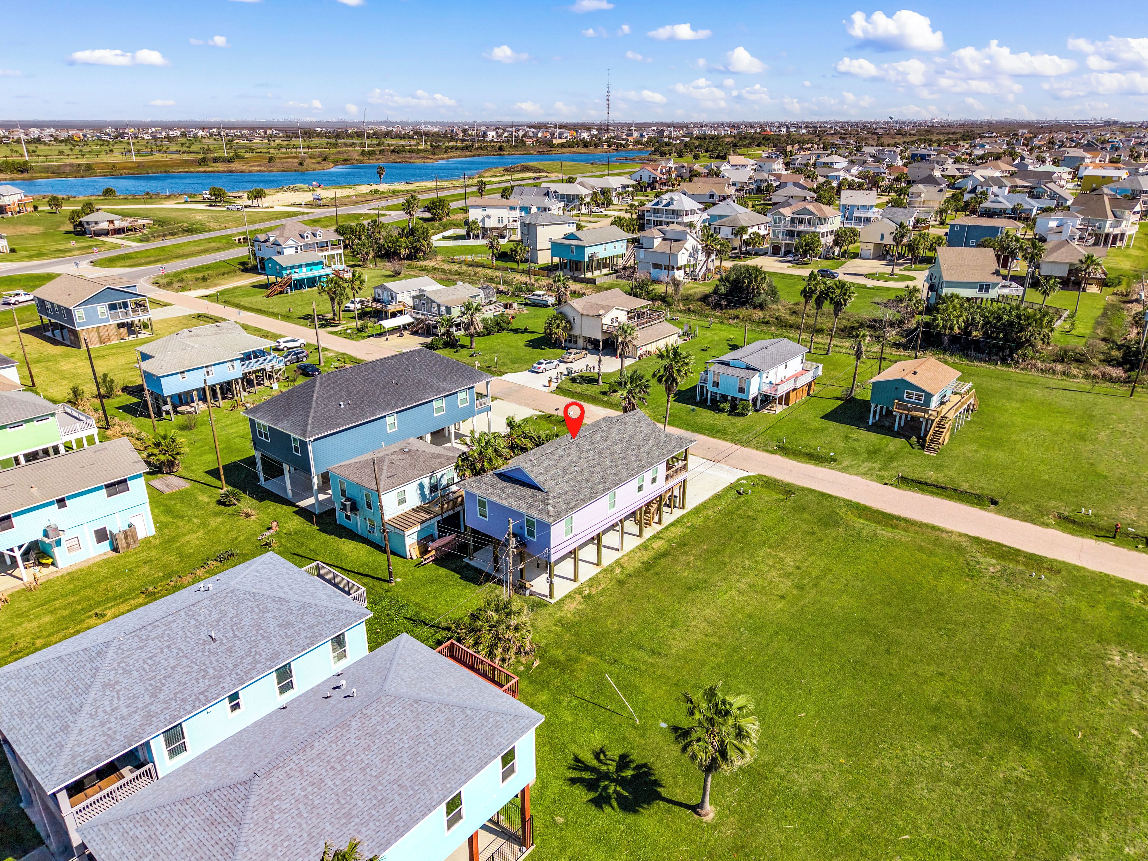An aerial view of a residential area with houses, a body of water, and a clear sky.