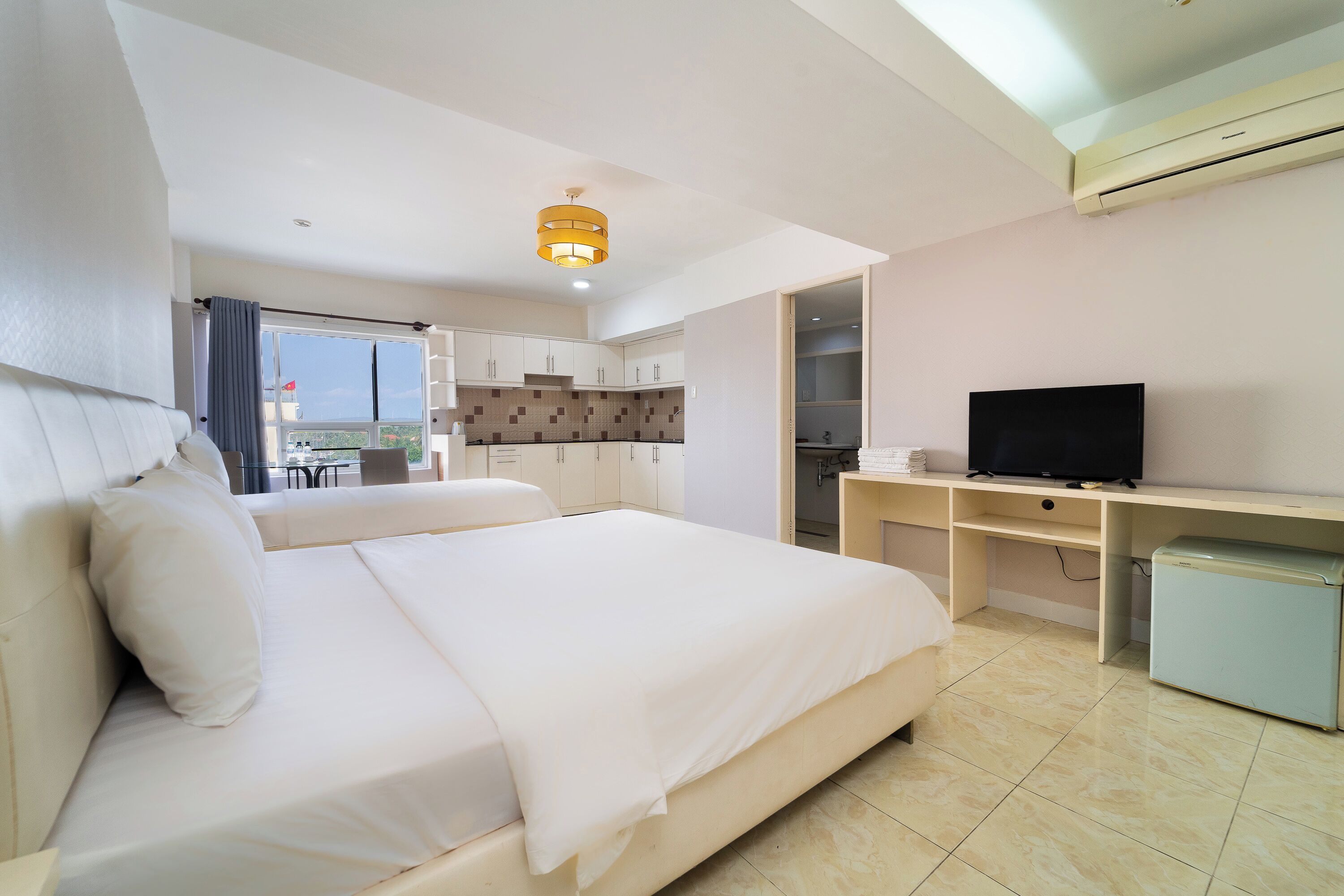 A hotel room with a bed, a TV, a desk, and a mini-fridge.