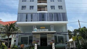 A multi-story hotel with a modern facade, balconies on each floor, and a ground-level boutique. - Palette Muine Boutique Hotel Near Mui Ne Beach (1 Bao Loc)