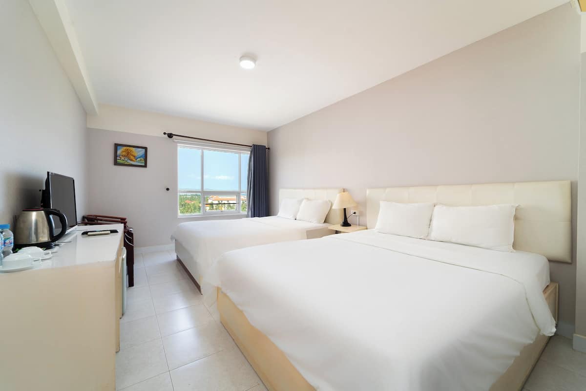 Ett hotellrum med två sängar, ett skrivbord med en vattenkokare och ett fönster med utsikt.