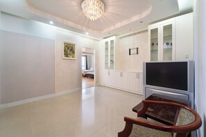 A spacious living room with a flat-screen TV, wooden furniture, and a chandelier. - Palette Muine Boutique Hotel Near Mui Ne Beach (Bao Loc)