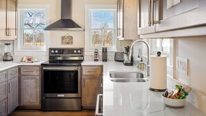 Una cocina moderna con electrodomésticos de acero inoxidable, armarios de madera y un amplio ventanal que proporciona luz natural.