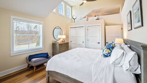 Un dormitorio con cama, ventilador de techo, ventana con persianas, mesita de noche y cómoda.